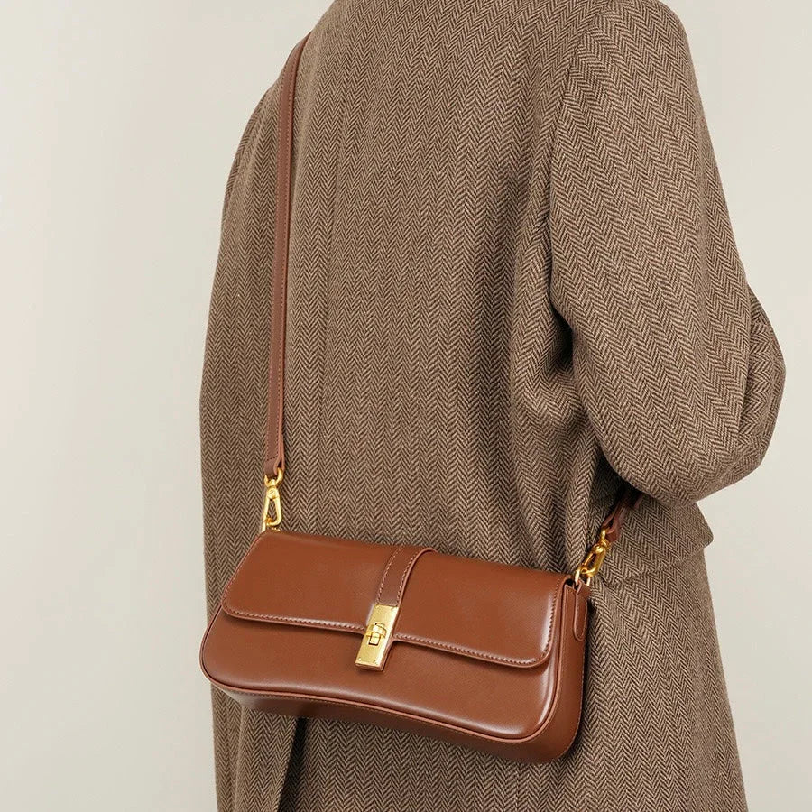 Brown leather shoulder bag with gold clasp on person in herringbone coat