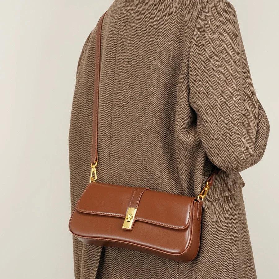 Brown leather shoulder bag with gold clasp on person in herringbone coat