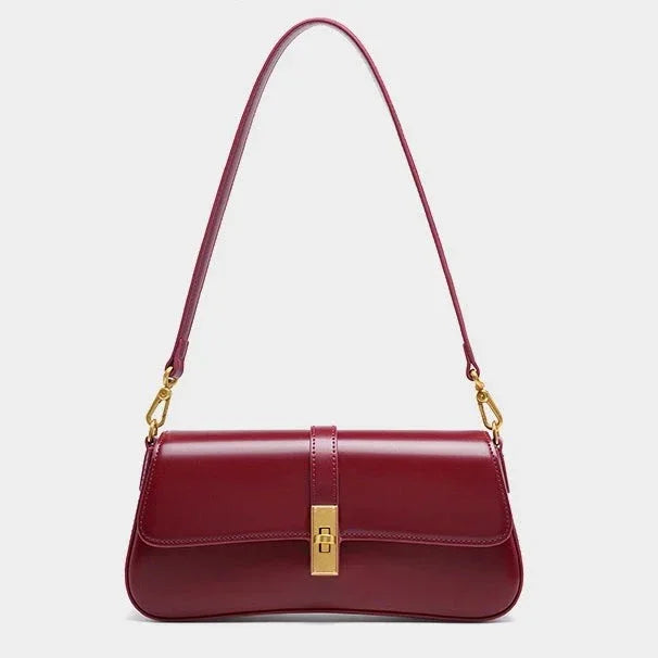Sleek burgundy leather shoulder bag with gold clasp and hardware on a plain background