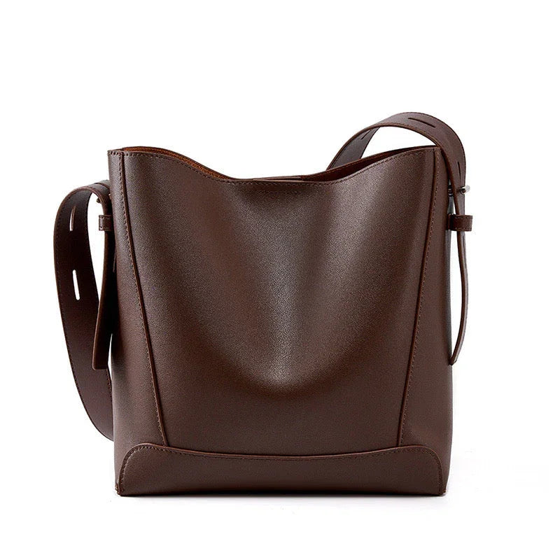 Brown leather bucket bag with wide adjustable strap on white background