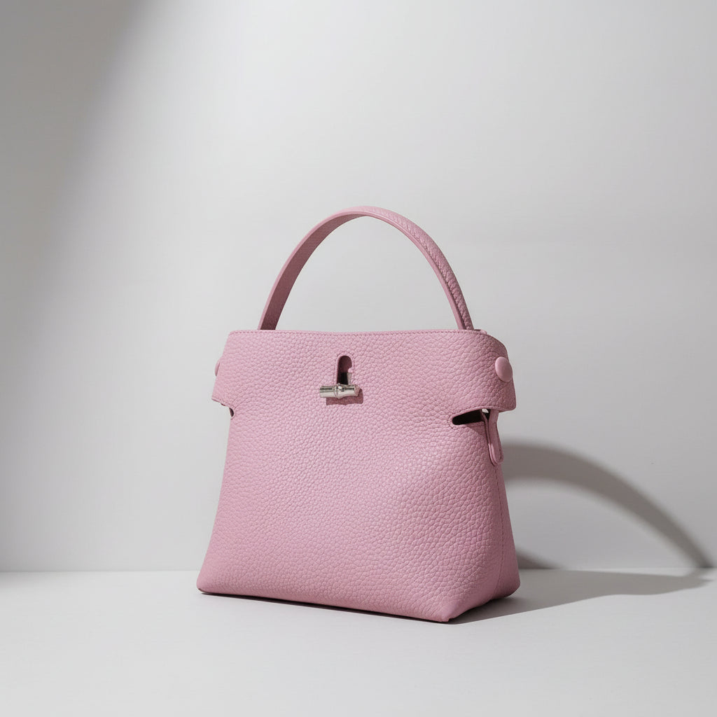 Textured pink leather handbag with silver clasp on a beige background