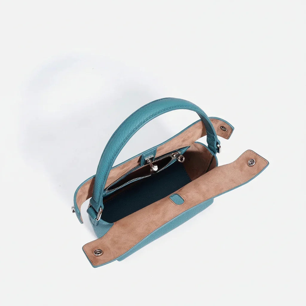 Top view of open teal leather handbag with brown suede interior and zipper pocket