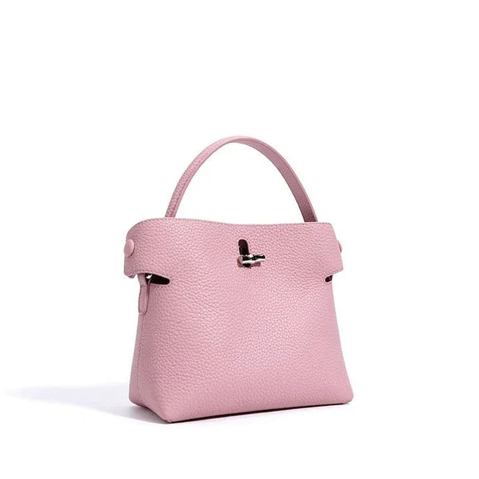 Light pink textured leather handbag with top handle on white background