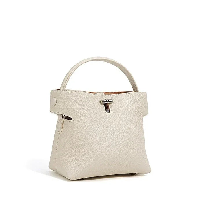 Cream leather handbag with top handle, minimalist style, silver clasp, on white background