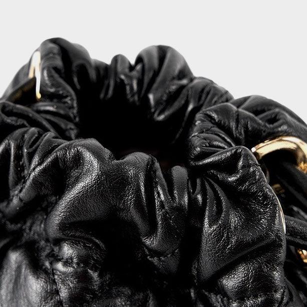 Black leather ruched bag with gold hardware, close-up on gathered drawstring opening