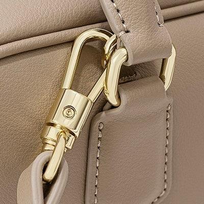 Beige leather handbag with gold hardware clasp and detailed stitching