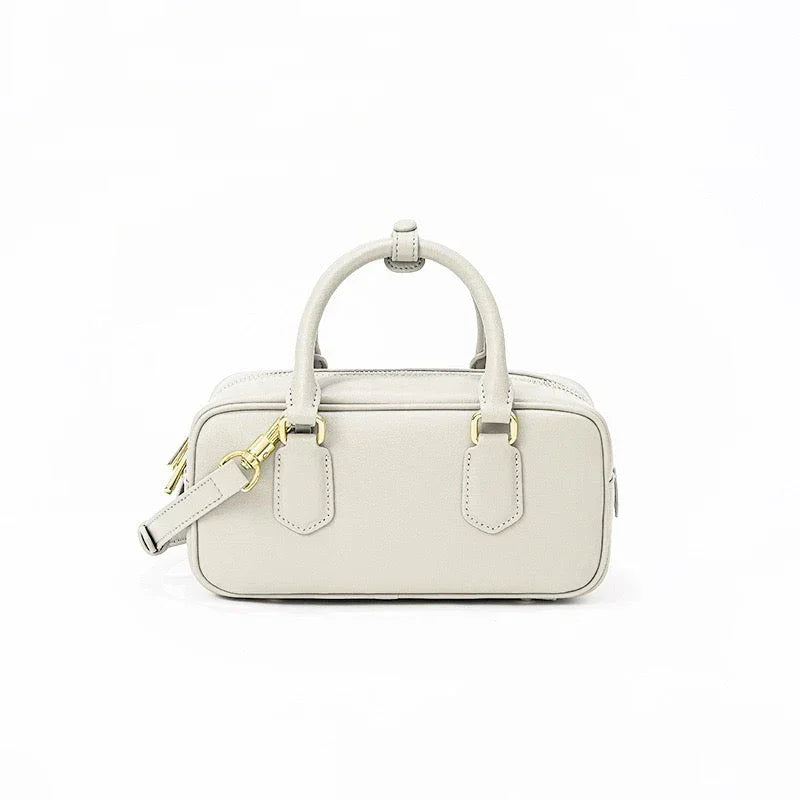 Beige rectangular leather handbag with gold hardware and top handles on white background