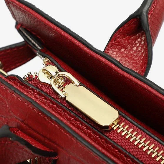Close-up of red leather handbag with gold zipper and textured finish