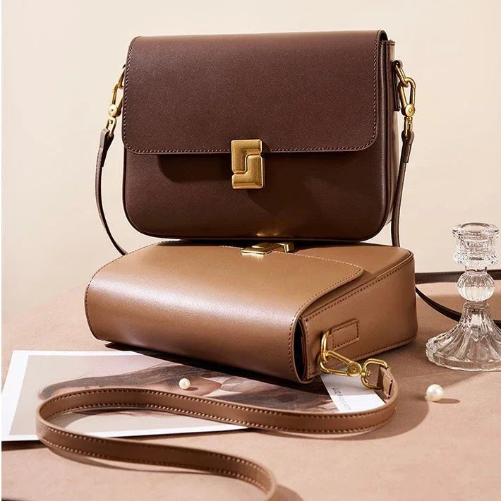 Two stylish leather crossbody bags in brown tones with gold hardware on a neutral background