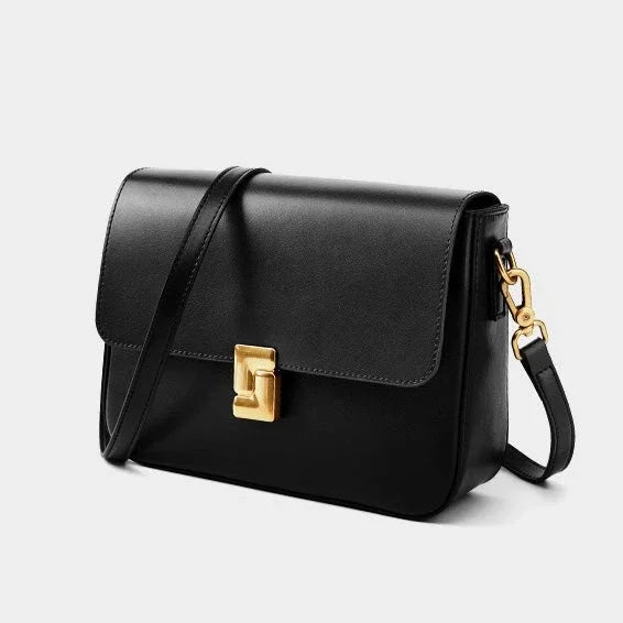 Black leather crossbody bag with gold clasp and minimalist design on white background