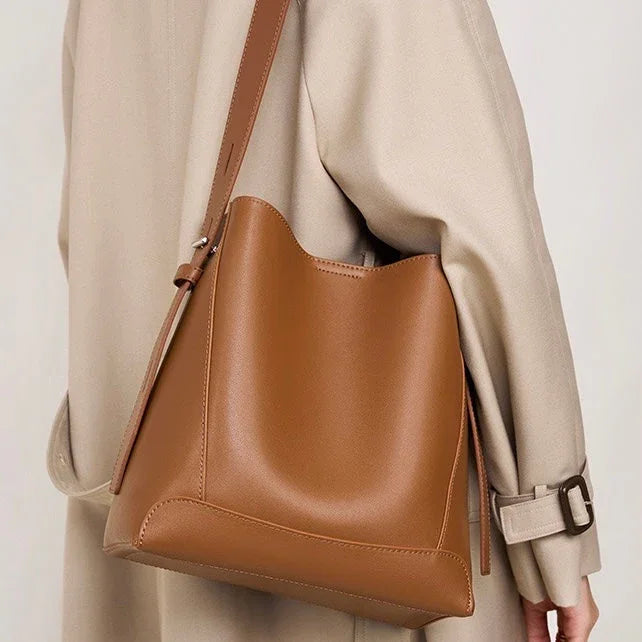 Woman wearing beige trench coat with large brown leather shoulder bag