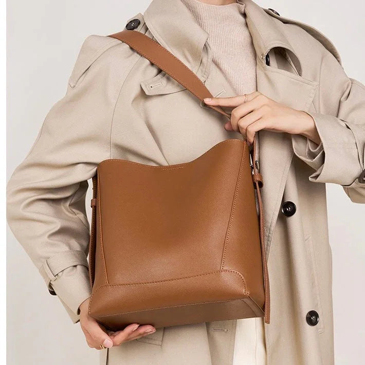 Woman in beige trench coat holding a brown leather shoulder bag