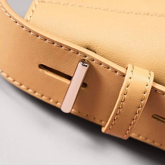 Close-up of tan leather bag strap with gold buckle and detailed stitching