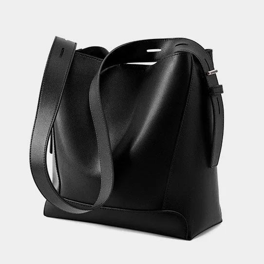 Minimalist black leather bucket bag with adjustable strap on a white background