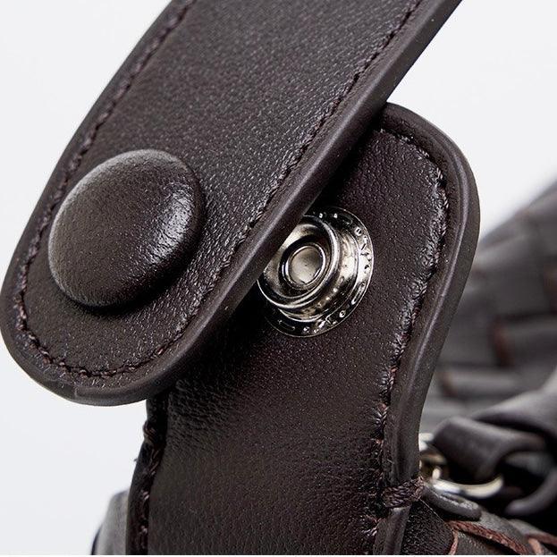 Close-up of dark brown leather bag strap with metal snap button clasp