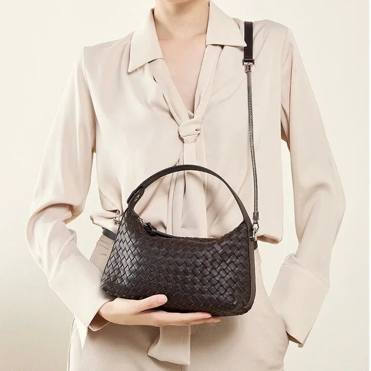 Woman in beige blouse holding a black woven leather shoulder bag