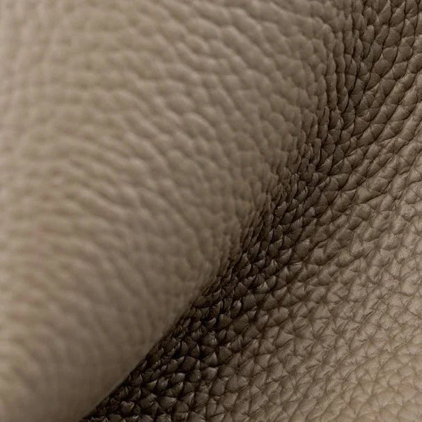 Close-up of beige pebbled leather texture with natural grain folds, luxury upholstery material