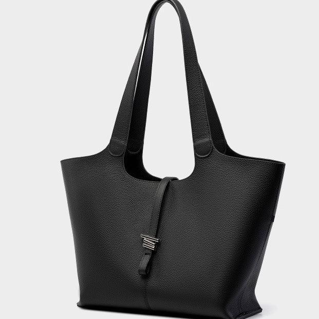 Black leather tote bag with double handles and silver clasp against white background