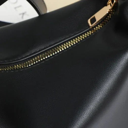 Close-up of black leather handbag with gold zipper detail