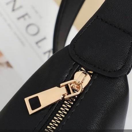 Black leather handbag with gold zipper detail on magazine background