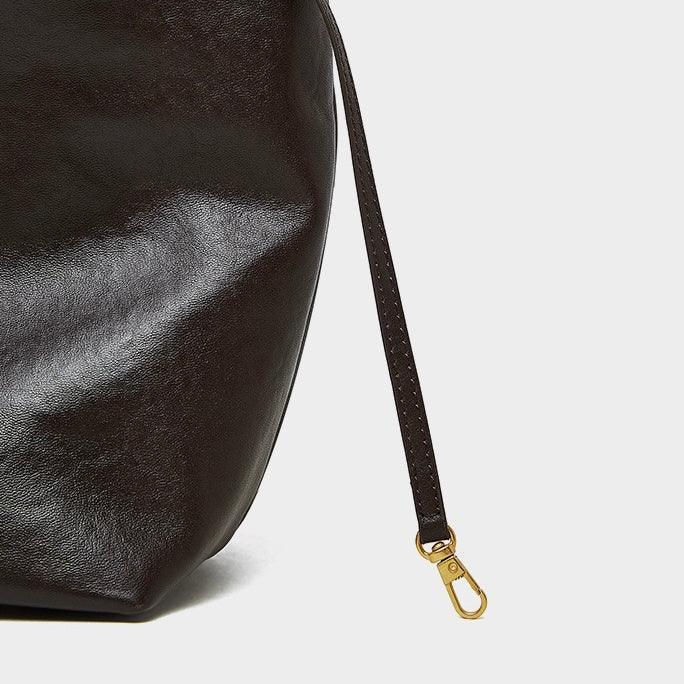 Close-up of dark brown leather bag with gold clasp on white background