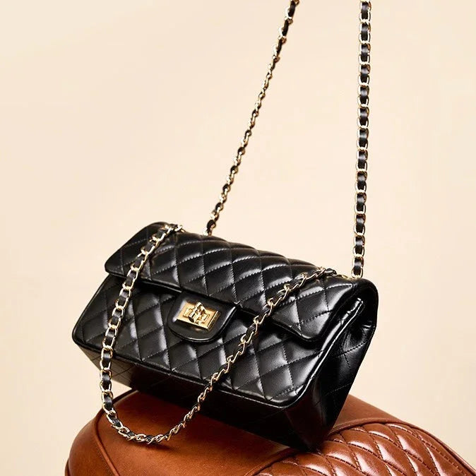 Black quilted leather handbag with gold chain strap and clasp on a brown surface