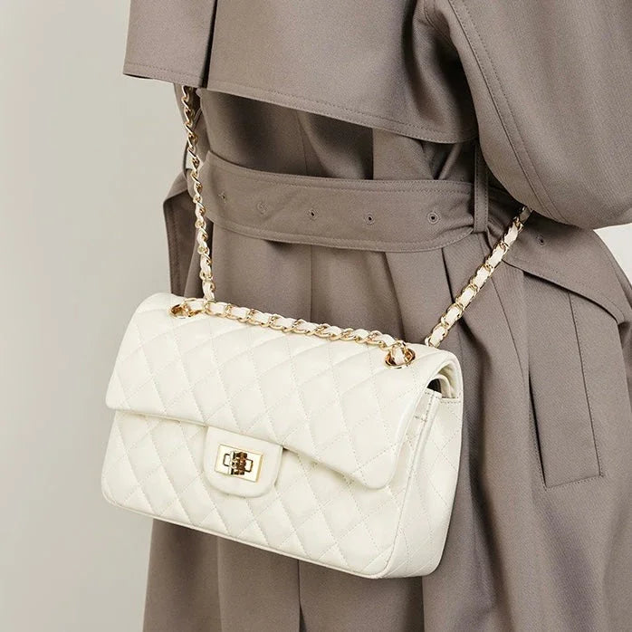 Quilted white leather handbag with gold chain strap on woman in taupe trench coat