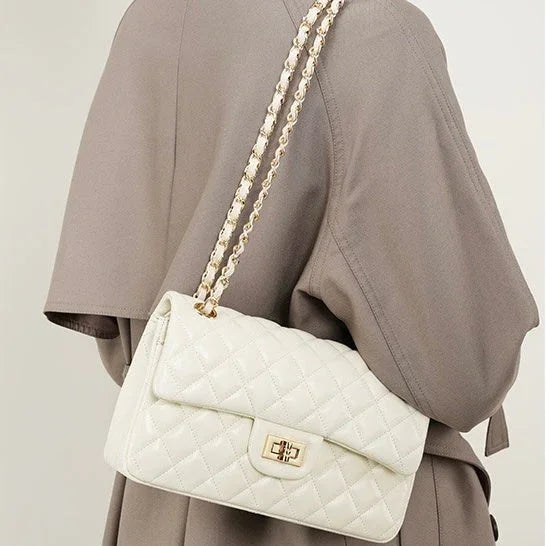 Quilted white leather shoulder bag with gold chain strap on person in taupe coat