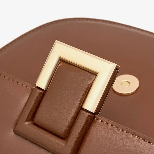 Close-up of brown leather handbag with gold square buckle detail