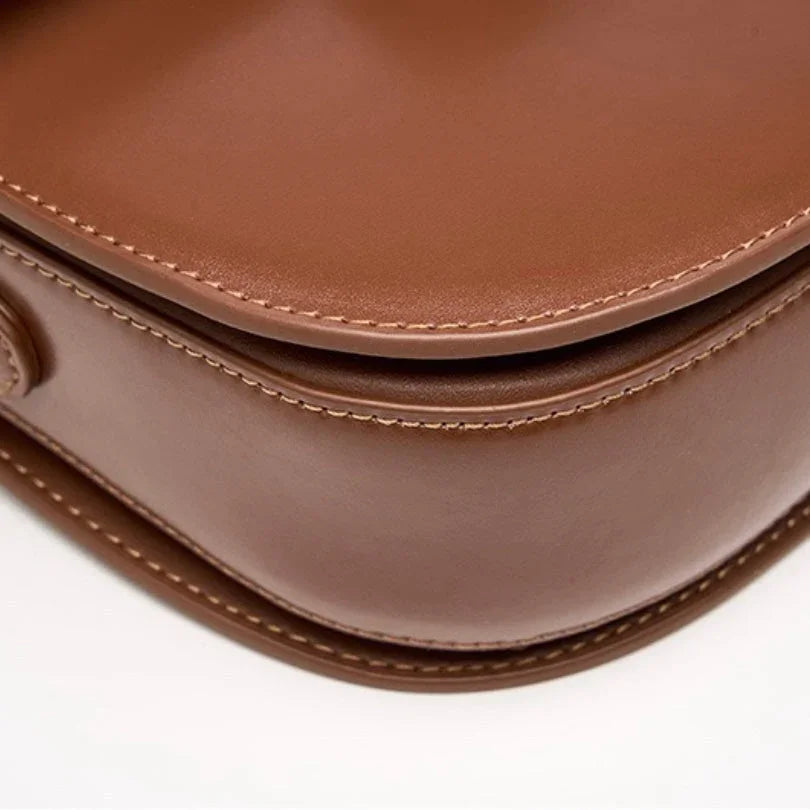 Close-up of brown leather handbag with detailed stitching on white background