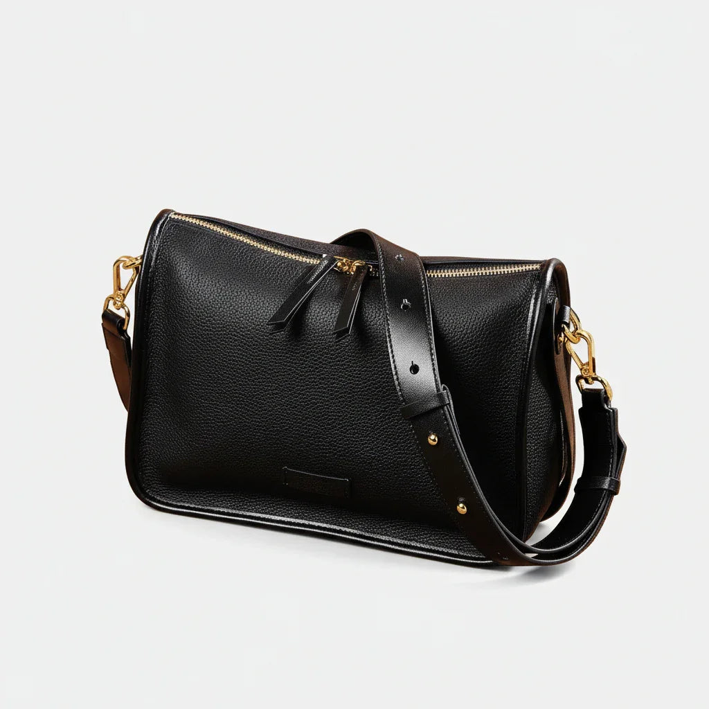 Black leather handbag with gold hardware on woven mat, rustic decor, dried flowers