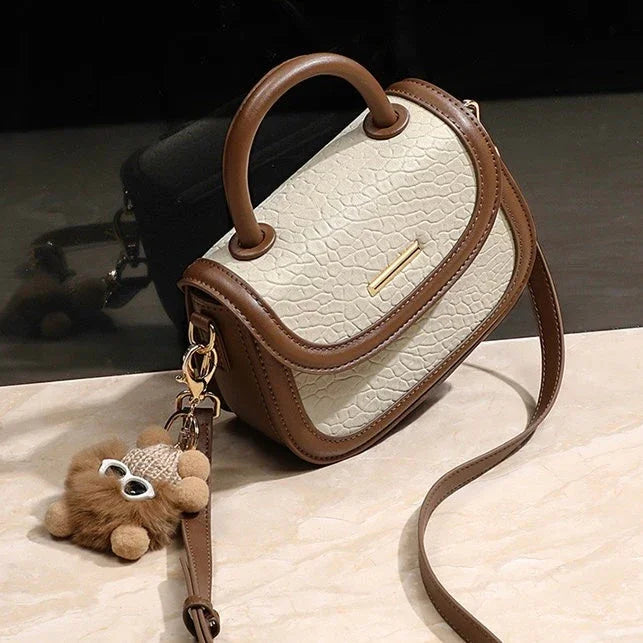 Beige and brown textured leather crossbody handbag with handle and plush bear keychain