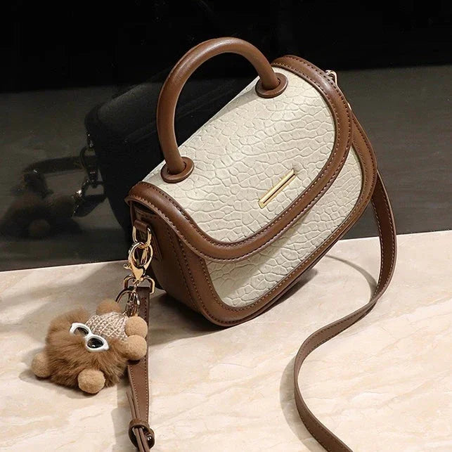 Beige and brown textured leather crossbody handbag with handle and plush bear keychain
