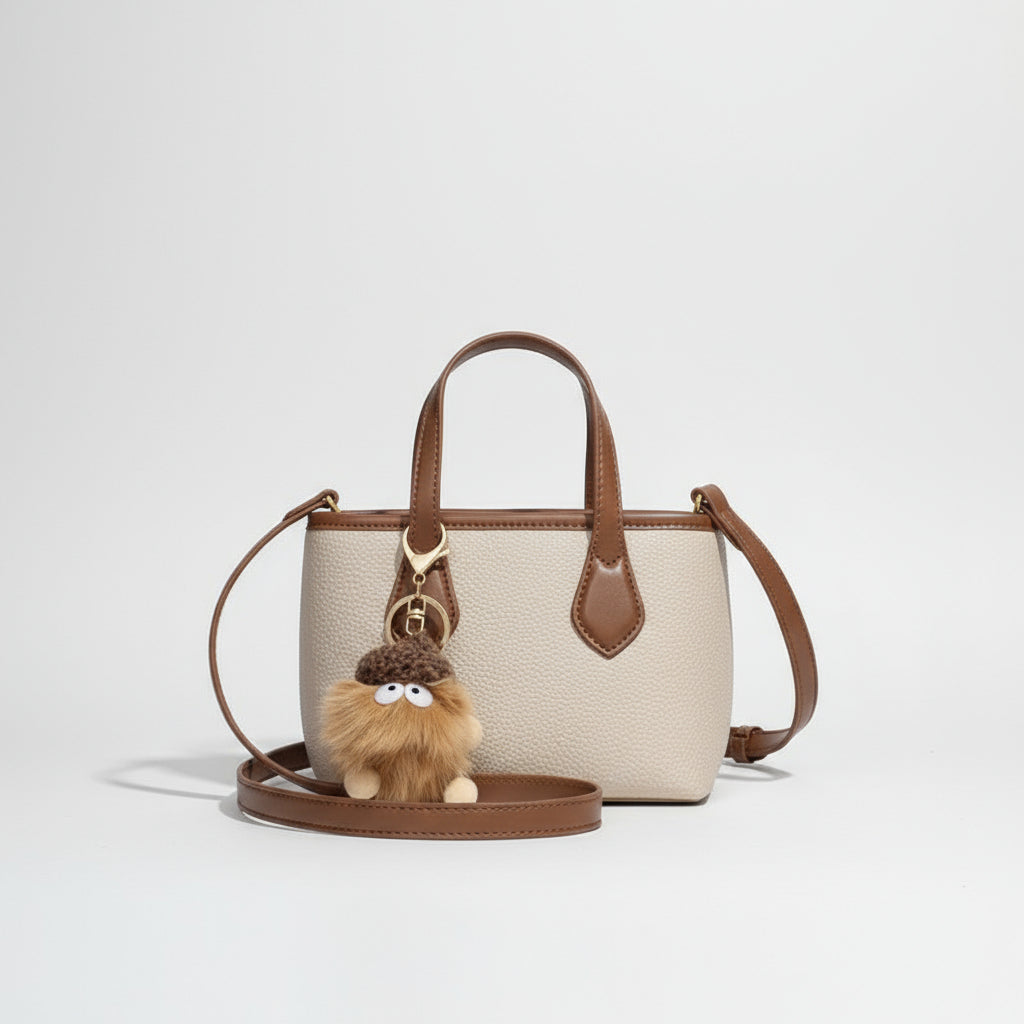Beige and brown leather crossbody bag with plush pom pom keychain accessory