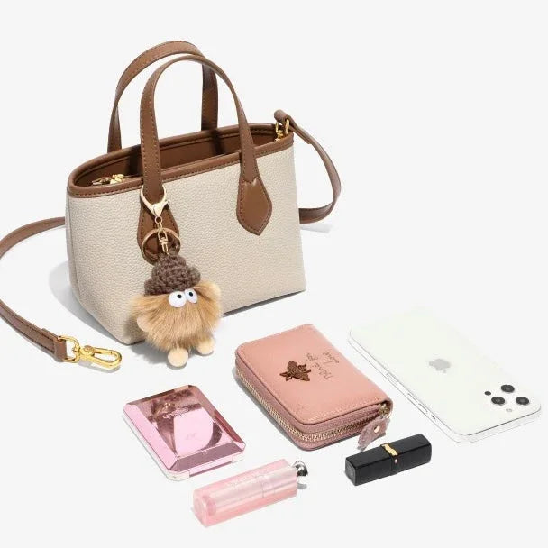 Beige mini tote bag with brown straps, fuzzy keychain, phone, cosmetics, and pink wallet.