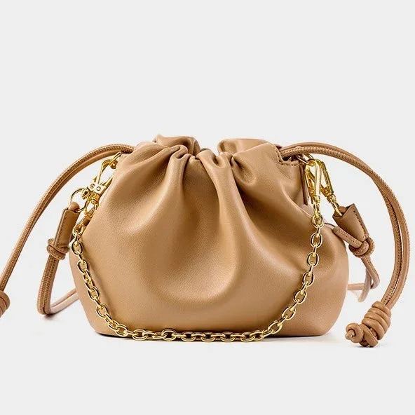 Tan leather drawstring purse with gold chain strap on white background