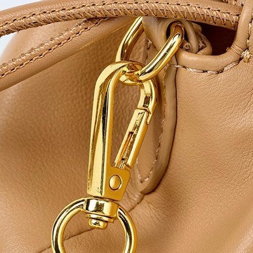 Closeup of gold metal clasp on tan leather handbag
