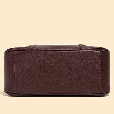 Bottom view of a brown leather handbag on a beige background