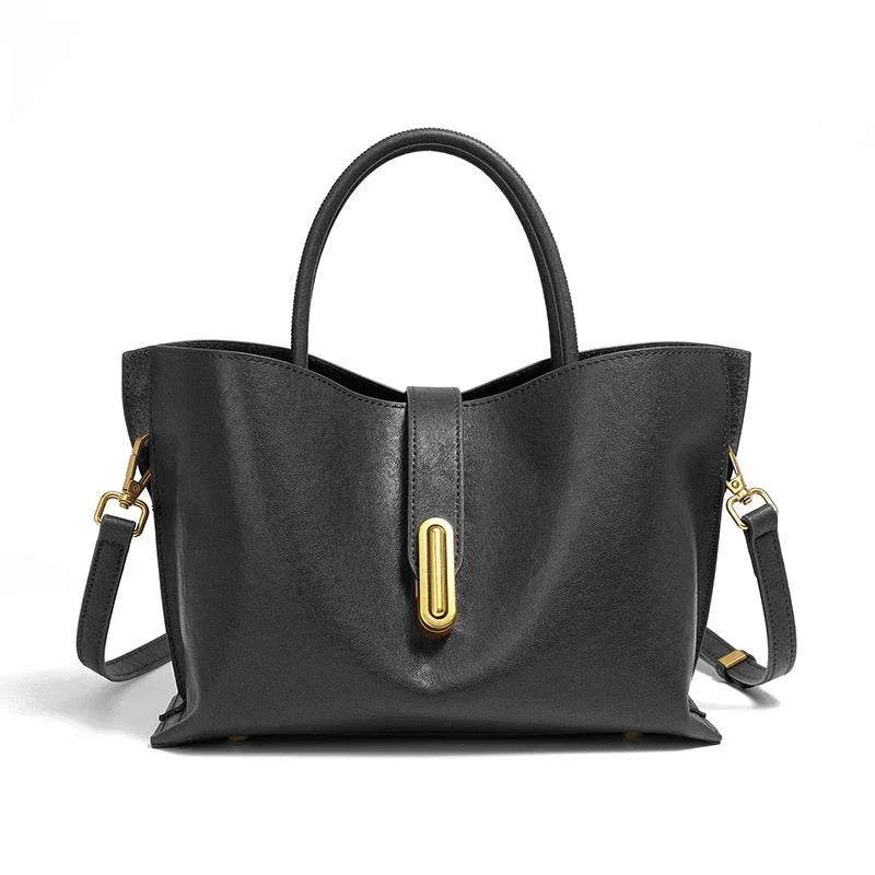 Black leather handbag with gold hardware and top handles on a white background