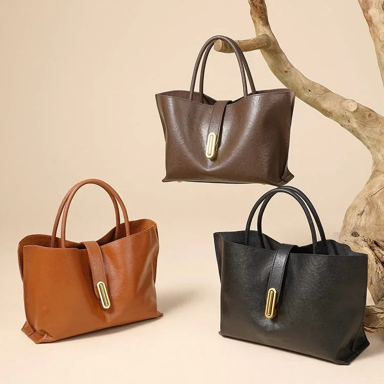 Three leather tote bags in brown, black, and tan on a beige background with a tree branch