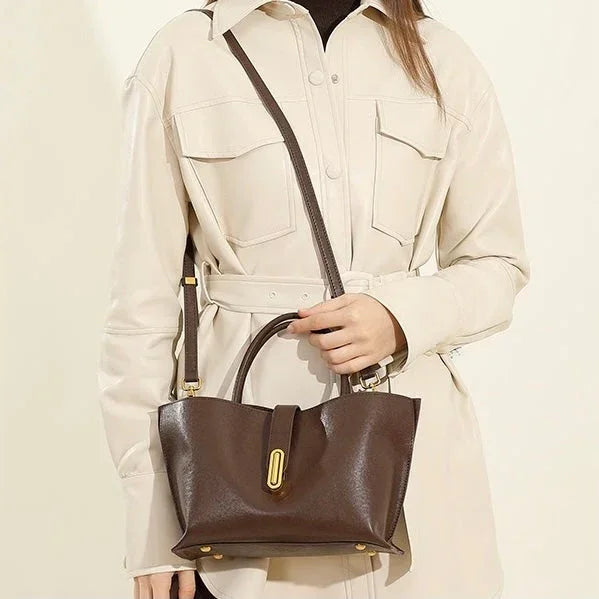 Woman in beige belted shirt dress holding brown leather handbag with gold hardware