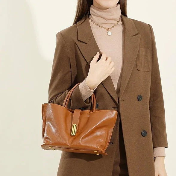 Woman in brown blazer and turtleneck holding a brown leather handbag