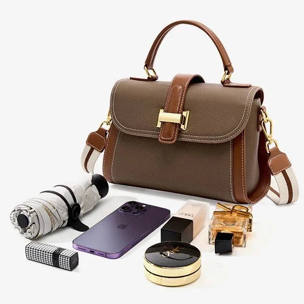 Taupe leather handbag with gold clasp, phone, perfume, makeup, and umbrella on white background