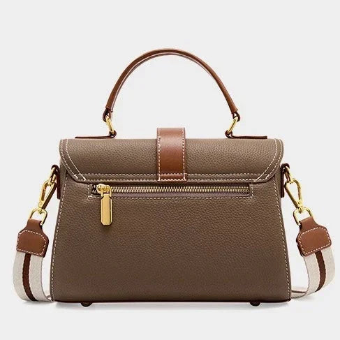 Taupe leather handbag with gold zipper, brown top handle, and striped shoulder strap
