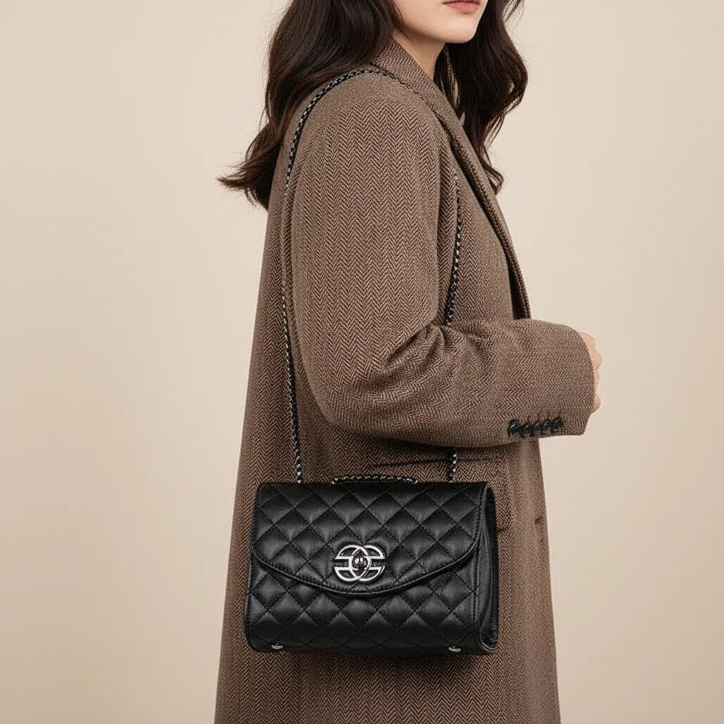 Black quilted leather shoulder bag with chain strap and silver logo on brown herringbone coat