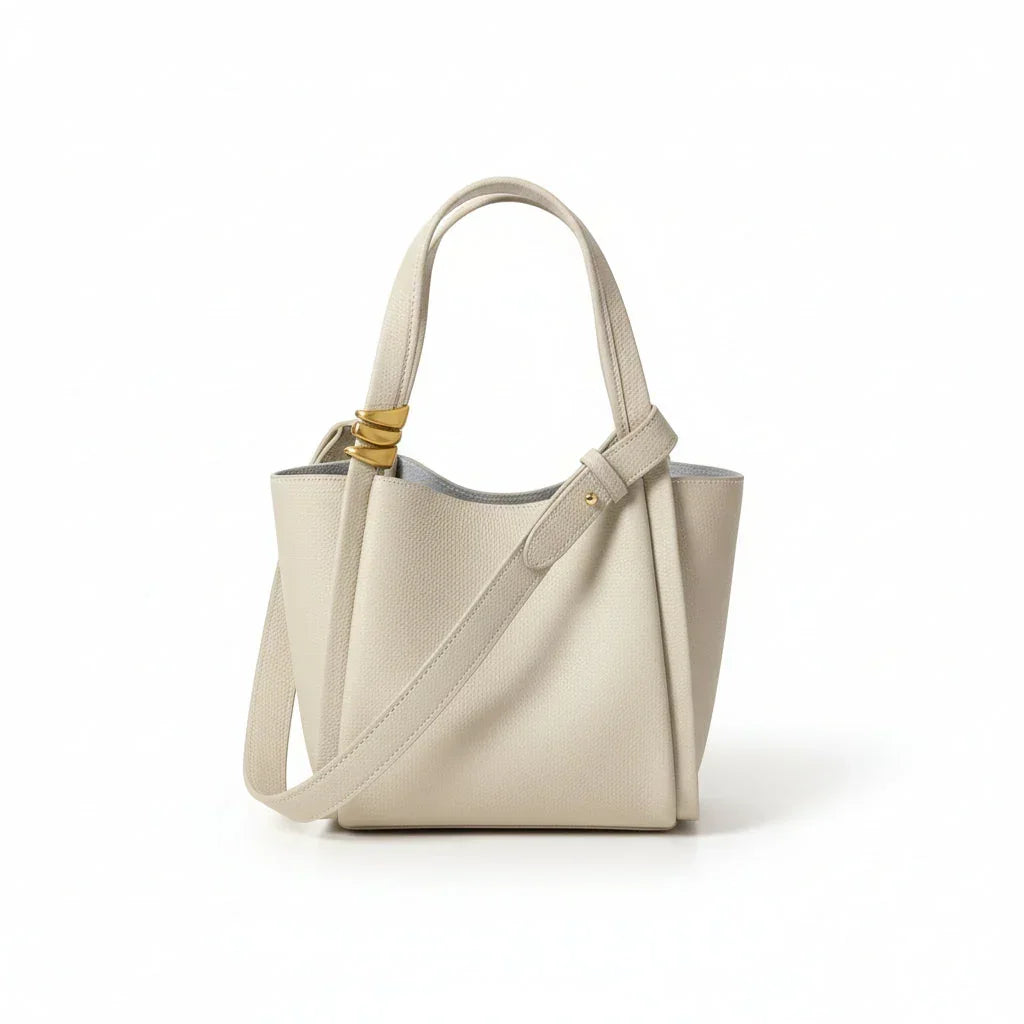 Beige leather tote bag with shoulder strap and gold hardware on white background