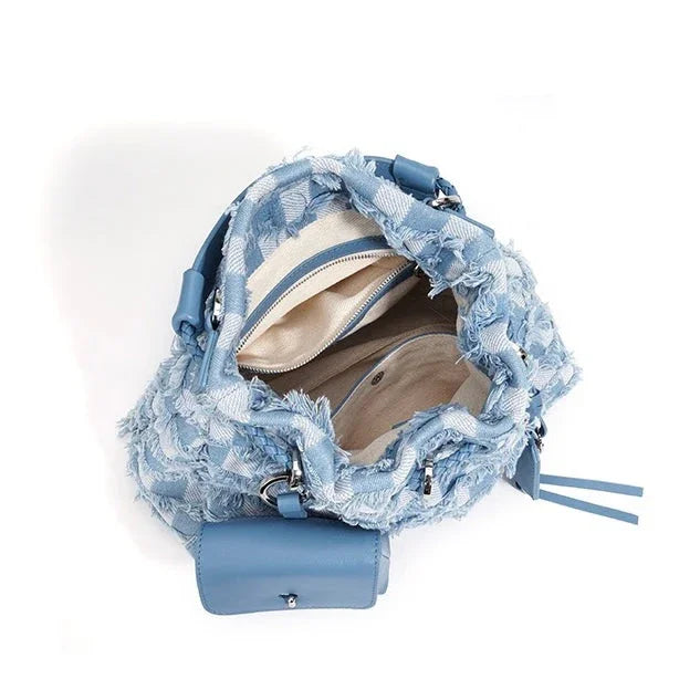 Open blue textured handbag with beige interior, zipper pocket, and leather accents