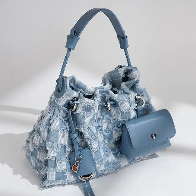 Blue patchwork denim handbag with braided handle and front pocket on white background