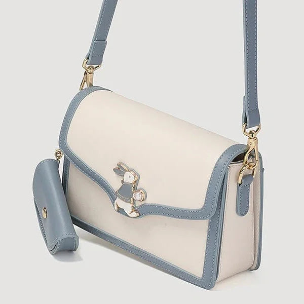 Cream and blue shoulder bag with bunny clasp and matching pouch on light background