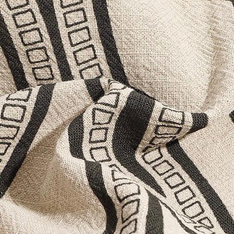 Beige textured fabric with black geometric striped square pattern, modern textile design